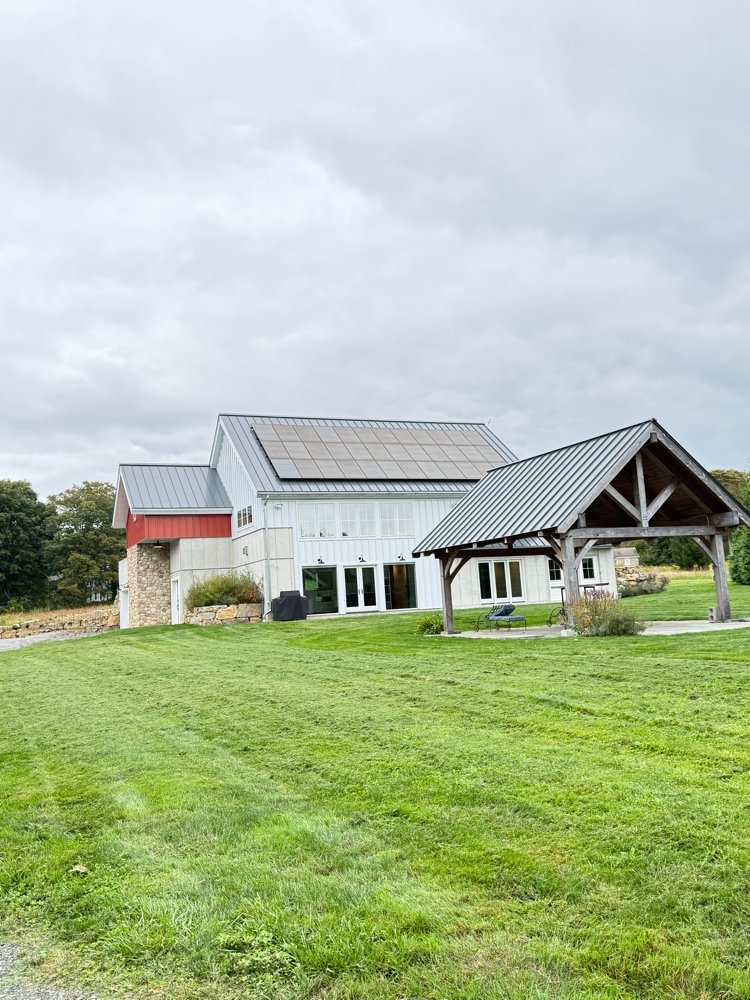 Modern barn-style home in Stonington, CT with standing-seam metal roof and timber-framed porch