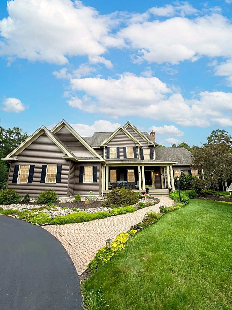 Colonial family home in Stonington, CT with taupe siding, cream trim, black shutters and a covered front porch